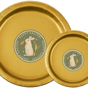 May include: Two gold-coloured paper plates, one large and one small, with a textured finish. Each plate features a circular sticker with a white rabbit holding a flower, with the words "HAPPY EASTER!"