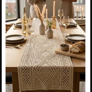 May include: A dining table set for a gathering, featuring a cream-colored, intricately crocheted table runner with diamond patterns and tassels. The table is set with plates, glasses, candles, and a bottle of wine, creating an elegant and inviting atmosphere.