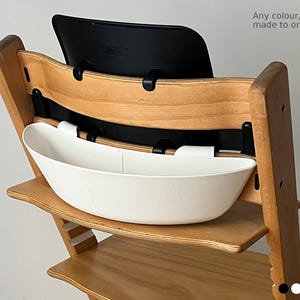 May include: Wooden high chair with a white plastic tray and black backrest. The text "Any colour, made to order" is visible. The chair is made of light-colored wood.
