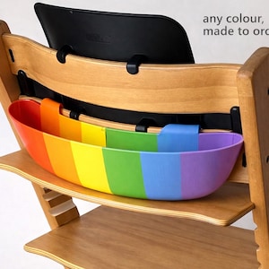 May include: Wooden high chair with a rainbow-colored storage container. The container is divided into vertical stripes of red, orange, yellow, green, blue, and purple. The text "any colour, made to order" is visible.