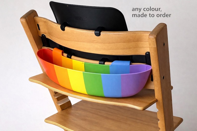 May include: Wooden high chair with a rainbow-colored storage container. The container is divided into vertical stripes of red, orange, yellow, green, blue, and purple. The text "any colour, made to order" is visible.