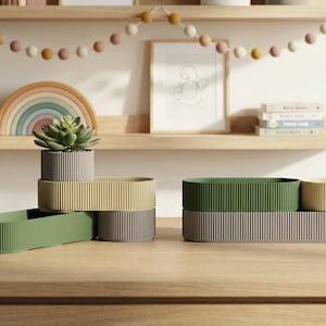 May include: A collection of decorative planters in various colors, including green, yellow, and gray. The planters have a ribbed texture and are arranged on a wooden surface. A succulent plant is in one of the planters.