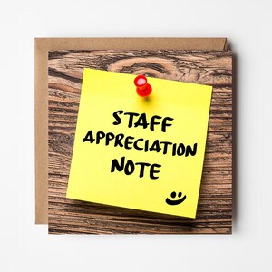 May include: A yellow sticky note with the words "STAFF APPRECIATION NOTE" in black, pinned to a wooden surface with a red pin. A small smiley face is at the bottom. The note is on a brown card.