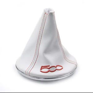 May include: White shift boot with red stitching and the embroidered number "500" in red. The boot has a silver-coloured trim at the base. This is likely an automotive interior accessory.