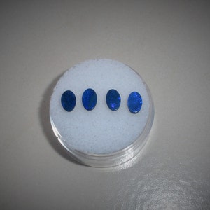 May include: Four oval-shaped blue opals in a white foam container.