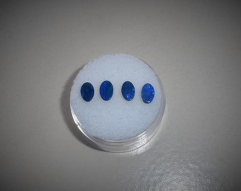 May include: Four oval-shaped blue opals in a white foam container.