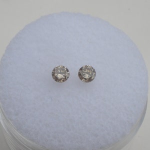 May include: Two round, brown diamonds on a white background.