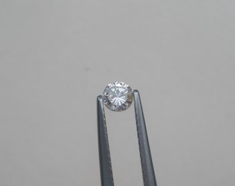 May include: A clear round diamond gemstone held by silver tweezers.