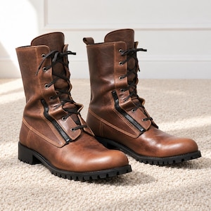 May include: A pair of mid-calf brown boots featuring a distressed leather-like finish, black laces, and a prominent black side zipper detail. The boots have a rounded toe, a structured shaft, and a thick, black lugged rubber sole for traction.