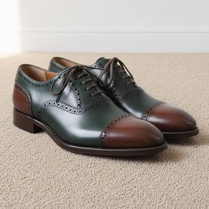 Pair of green and brown cap toe oxford shoes with brogue detailing on beige carpet
