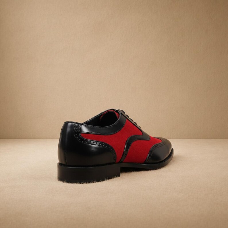 Side profile of men's black and red two-tone wingtip brogue oxford showing smooth leather upper, red suede panels, low stacked heel, and black leather outsole