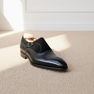 Front perspective of polished black monk strap dress loafers with sleek almond toe shape
