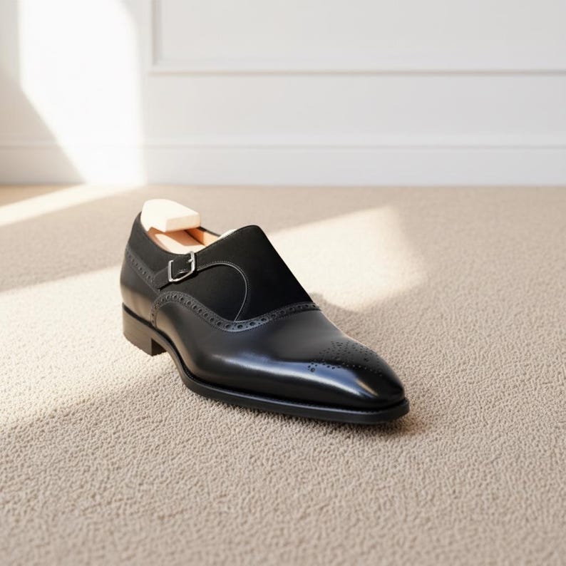 Front perspective of polished black monk strap dress loafers with sleek almond toe shape