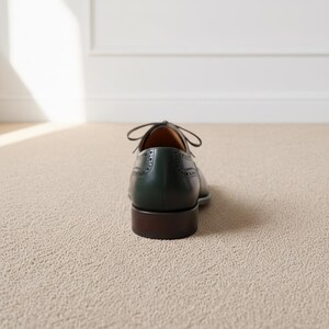Close-up of perforated cap toe detailing on luxury green and brown leather oxford shoes