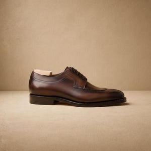May include: A brown leather dress shoe with a split-toe design. The shoe features a classic lace-up closure and a wooden shoe tree inside. The leather has a polished finish, and the sole is black. The shoe is approximately 12 inches long.