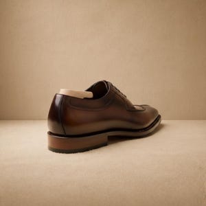 May include: A brown leather dress shoe with a cap toe design. The shoe has a polished finish and a wooden shoe tree inside. The heel is approximately 1 inch high. The shoe is displayed on a neutral background.