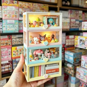 May include: A four-tier stackable storage display case with clear front panels and heart-shaped knobs. Each level features internal lighting and contains various miniature figurines, including cartoon characters and a row of small books on the bottom shelf.