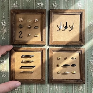 Op de afbeelding: Vier ingelijste displays met miniatuur hardware. De displays tonen diverse knoppen, handgrepen en haken in goud, zwart en zilver. Het nummer "2" is zichtbaar op een van de displays. De frames zijn gemaakt van hout.