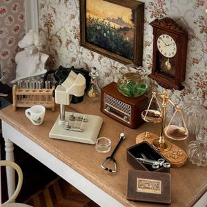 Può includere: Collezione in miniatura di strumenti medici e scientifici vintage su un tavolo di legno. Include un microscopio, una bilancia, provette, uno stetoscopio e una piccola radio. Un piccolo dipinto e un orologio sono sulla carta da parati floreale.