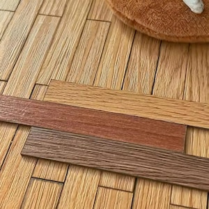 Könnte beinhalten: Drei Holzfußbodenmuster in verschiedenen Brauntönen, von hell bis dunkel. Sie werden auf einem hellbraunen Holzboden präsentiert und zeigen die Farbvarianten für Heimwerkerprojekte. Die Muster sind in cm.