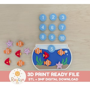 May include: A 3D printed fishbowl toy set featuring a blue bowl with green seaweed and brown sand, accompanied by orange clownfish, red fish, and purple starfish pieces. Includes numbered blue circular tokens from 1 to 10 for counting.