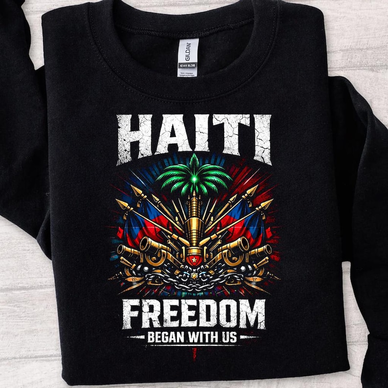 May include: Black sweatshirt with a graphic design featuring the word "HAITI" above a central emblem with a palm tree, flags, and weapons. The text "FREEDOM BEGAN WITH US" is below the emblem.