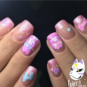 Może przedstawiać: Zbliżenie na manicure z różowym i białym wzorem. Paznokcie przedstawiają postać z kreskówki, kokardy i akcenty chmur. Paznokcie mają różowy brokatowy gradient i przezroczystą bazę.