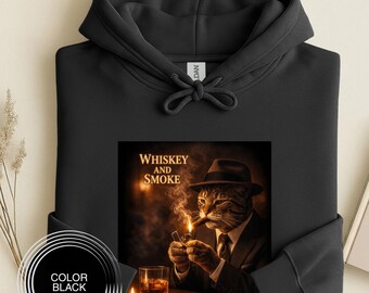 Könnte beinhalten: Schwarzer Kapuzenpullover mit einer Grafik einer Katze in Anzug, Hut und Krawatte, die eine brennende Zigarre und ein Feuerzeug neben einem Glas Whiskey hält. Die Grafik enthält den Text "Whiskey and Smoke".