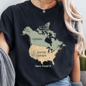May include: A black t-shirt featuring a map of North America with Canada in light green and the United States labelled as South Canada in light yellow. The text West Canada is printed in the north-west, and the phrase Here: fixed it. is below the map.