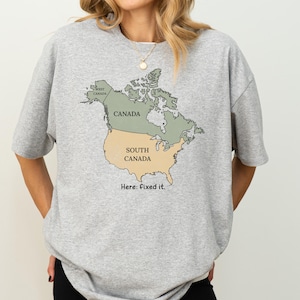 May include: A heather grey t-shirt featuring a graphic of the North American continent. The map is divided into two sections: the northern portion labeled Canada and the southern portion labeled South Canada. The text Here: fixed it. is below.