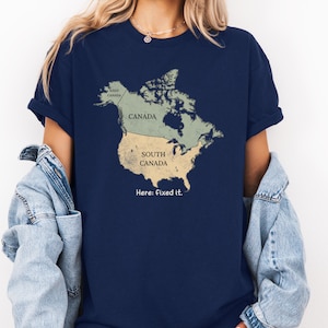 May include: A navy blue short-sleeve t-shirt featuring a graphic of North America. The map is divided into two sections labeled Canada and South Canada, with a small section labeled West Canada. The text below the map reads: Here: fixed it.