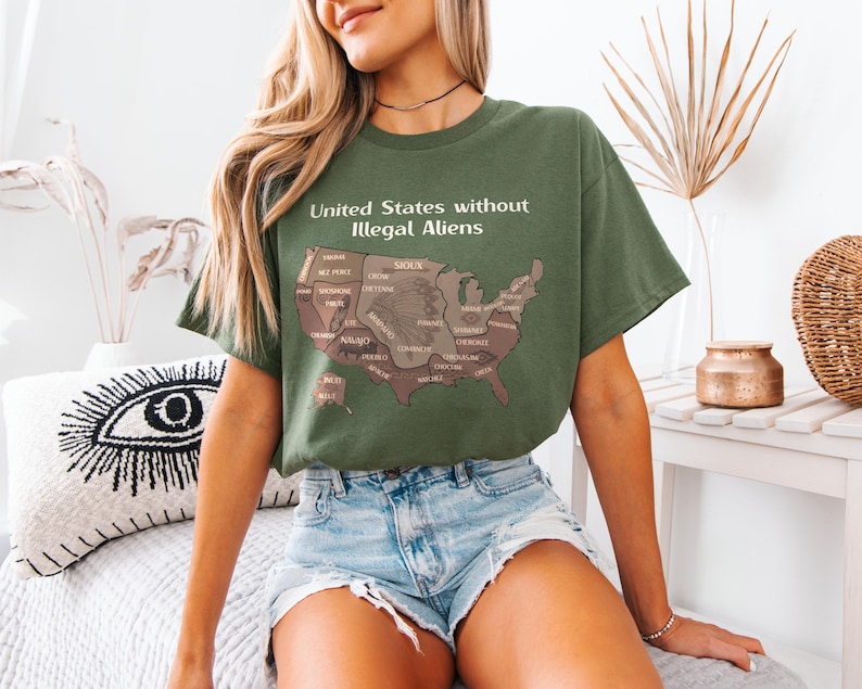 K&ouml;nnte beinhalten: Olivgr&uuml;nes T-Shirt mit dem Text "United States without Illegal Aliens" und einer braunen Karte der USA. Die Karte zeigt die Namen der Bundesstaaten. Das T-Shirt wird mit Jeansshorts getragen.