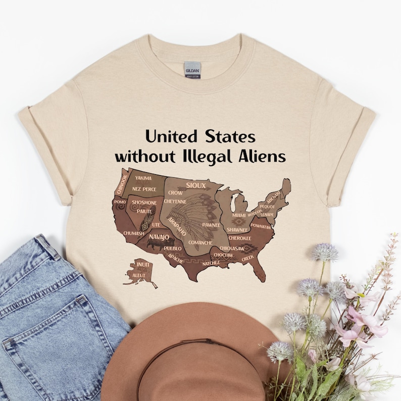 K&ouml;nnte beinhalten: Beiges T-Shirt mit dem Text "United States without Illegal Aliens" &uuml;ber einer braunen Karte der Vereinigten Staaten, mit Namen amerikanischer Ureinwohner. Eine blaue Jeans und ein brauner Hut sind ebenfalls im Bild.