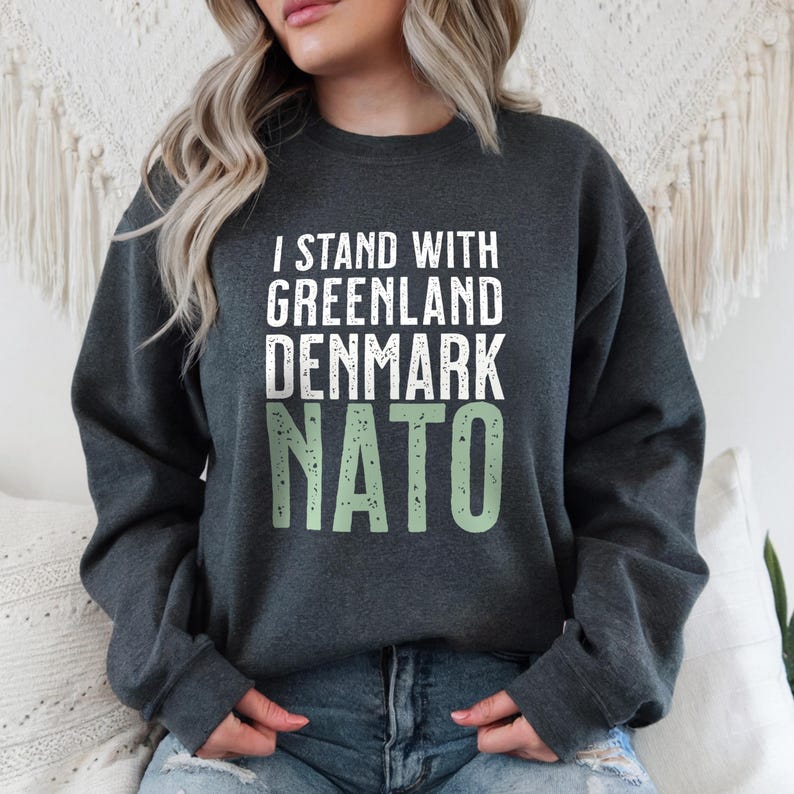 Op de afbeelding: Donkergrijze sweatshirt met de tekst "I STAND WITH GREENLAND DENMARK NATO" in wit en lichtgroen. De crew neck sweatshirt is gemaakt van een zacht materiaal.