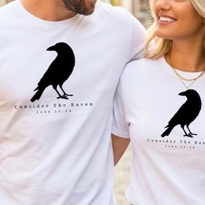 May include: White t-shirts with a black raven graphic and the text "Consider The Raven Luke 12:24". The raven is depicted in silhouette. The shirts are short-sleeved and appear to be made of cotton.
