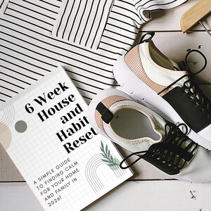 Peut inclure: Image d'un livre intitulé "6 Week House and Habit Reset" avec le texte "A SIMPLE GUIDE TO FINDING CALM FOR YOUR HOME AND FAMILY IN 2026!". On voit aussi une paire de baskets blanches et noires et un haut rayé noir et blanc.