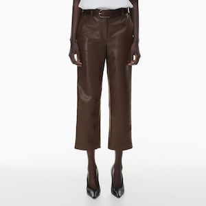 Può includere: Pantaloni marroni in ecopelle con cintura abbinata. I pantaloni sono tagliati alla caviglia e hanno una gamba dritta. La modella indossa tacchi neri. I pantaloni sono in tinta unita e hanno un design classico.