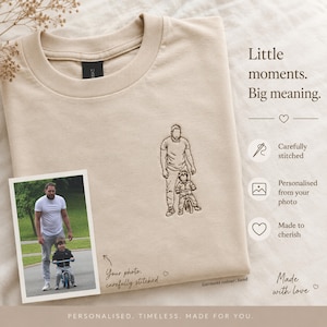 May include: A sand-coloured crewneck sweatshirt featuring a dark brown embroidered line art illustration of an adult and a child on a bicycle. The text reads: Little moments. Big meaning. A photograph of the subjects is placed on the garment.