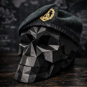 May include: A black geometric skull sculpture with a dark green beret. The beret features a gold emblem. The skull is constructed from numerous triangular facets, giving it a textured appearance. The background is a blurred map.
