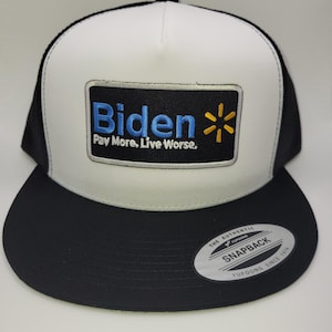 May include: A black and white trucker hat with a flat brim. The front panel is white with a patch that reads "Biden" in blue, with a yellow star and the text "Pay More, Live Worse."