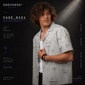 Può includere: Camicia grigio chiaro a maniche corte con stampa schematica, indossata sopra una maglietta bianca. La camicia presenta il testo "CASE_0151" e "OBJECT". Il modello indossa un braccialetto nero. Collezione 2024.