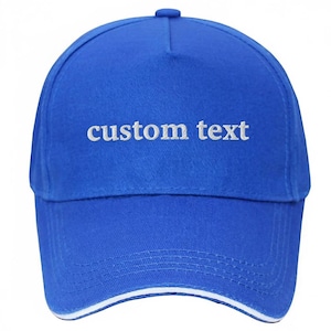 May include: A royal blue baseball cap with a curved brim and a white trim. The cap features the embroidered text "custom text" in white, centered on the front. The cap is made of a durable fabric and has a button on top.