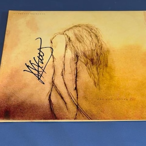 May include: A signed album cover with a sepia-toned illustration of a figure with flowing hair. The album cover has a handwritten signature in black ink. The text "she you rolling for" is visible.