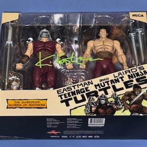 Puede incluir: Un set de figuras de acción NECA Teenage Mutant Ninja Turtles que incluye a The Shredder y un guerrero sin camisa en una caja con ventana. El empaque incluye el texto Eastman and Laird's Teenage Mutant Ninja Turtles y The Shredder: Worms of Madness.