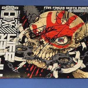 May include: A square music album cover for Five Finger Death Punch titled AfterLife. The artwork features a beige skull with a red handprint, biting a dark metal knuckle duster, surrounded by chains and black ink signatures across the surface.