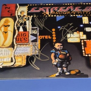 Op de afbeelding: Albumhoes voor Extreme II: Pornograffitti, met een cartoonjongen met bokshandschoenen en een sigaret. De hoes heeft neonreclame en handtekeningen. De albumtitel is in rood en geel.