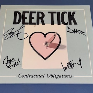 May include: A square light blue album cover titled DEER TICK and Contractual Obligations in black text. The centre features a pink heart graphic with a metal paperclip attached. Four distinct black ink signatures are positioned around the heart.