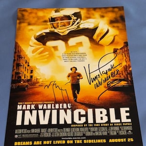 May include: Movie poster for "Invincible" starring Mark Wahlberg. The poster features a football player in a helmet and a man running. The title "Invincible" is prominently displayed, with the tagline "Dreams are not lived on the sidelines."