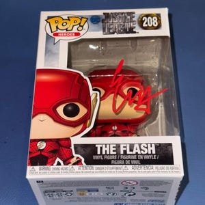 Może przedstawiać: Figurka winylowa Funko Pop Heroes Justice League The Flash, numer 208, w oryginalnym opakowaniu. Przezroczyste plastikowe okienko zawiera czerwony autograf z przodu. Pudełko prezentuje nazwę postaci oraz logo DC w kolorze białym i czarnym.