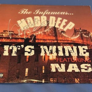 May include: Album cover for Mobb Deep's "It's Mine" featuring Nas. The cover features a cityscape with a bridge and buildings, with the album title and artist names in large, bold letters. The cover has a parental advisory warning.